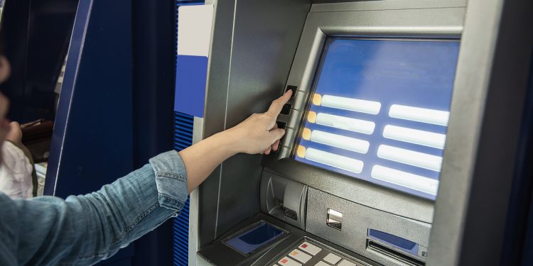 People waiting to get money from automated teller machine - people withdrawn money from ATM concept