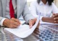Closeup shot of businessman signing documents. African American managers working with documents. Business concept