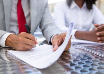 Closeup shot of businessman signing documents. African American managers working with documents. Business concept