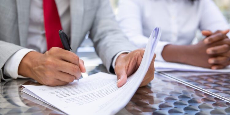 Closeup shot of businessman signing documents. African American managers working with documents. Business concept